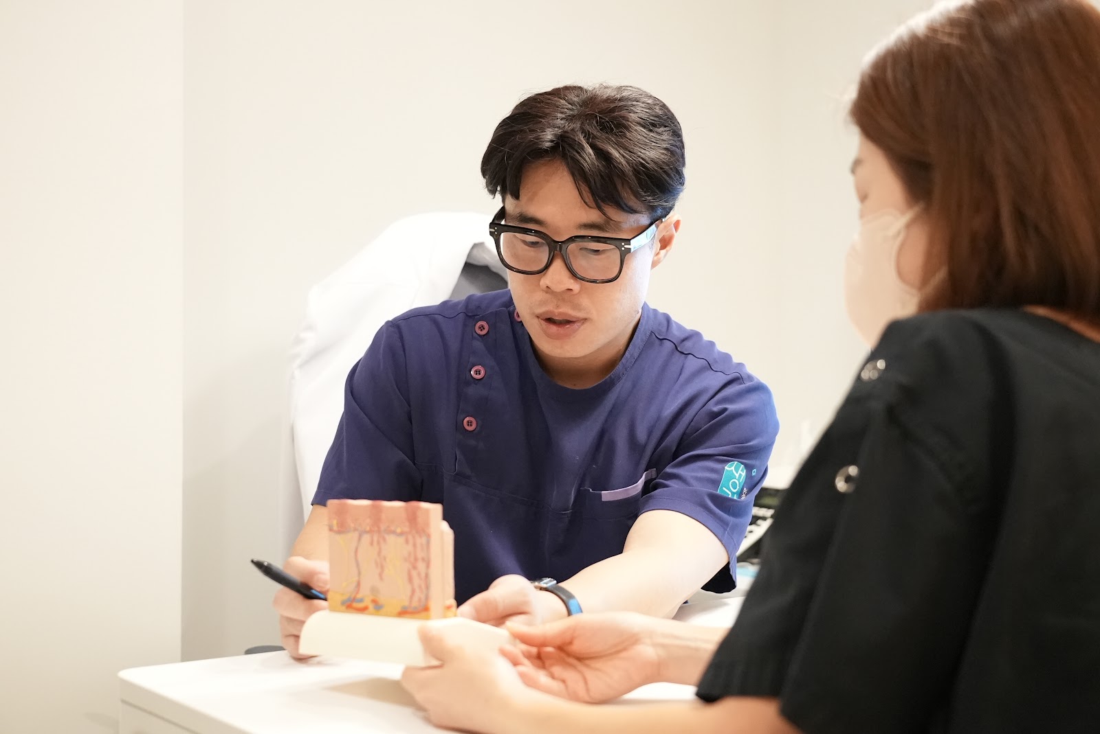 진료실에서 상담하며 피부 상태를 설명합니다.